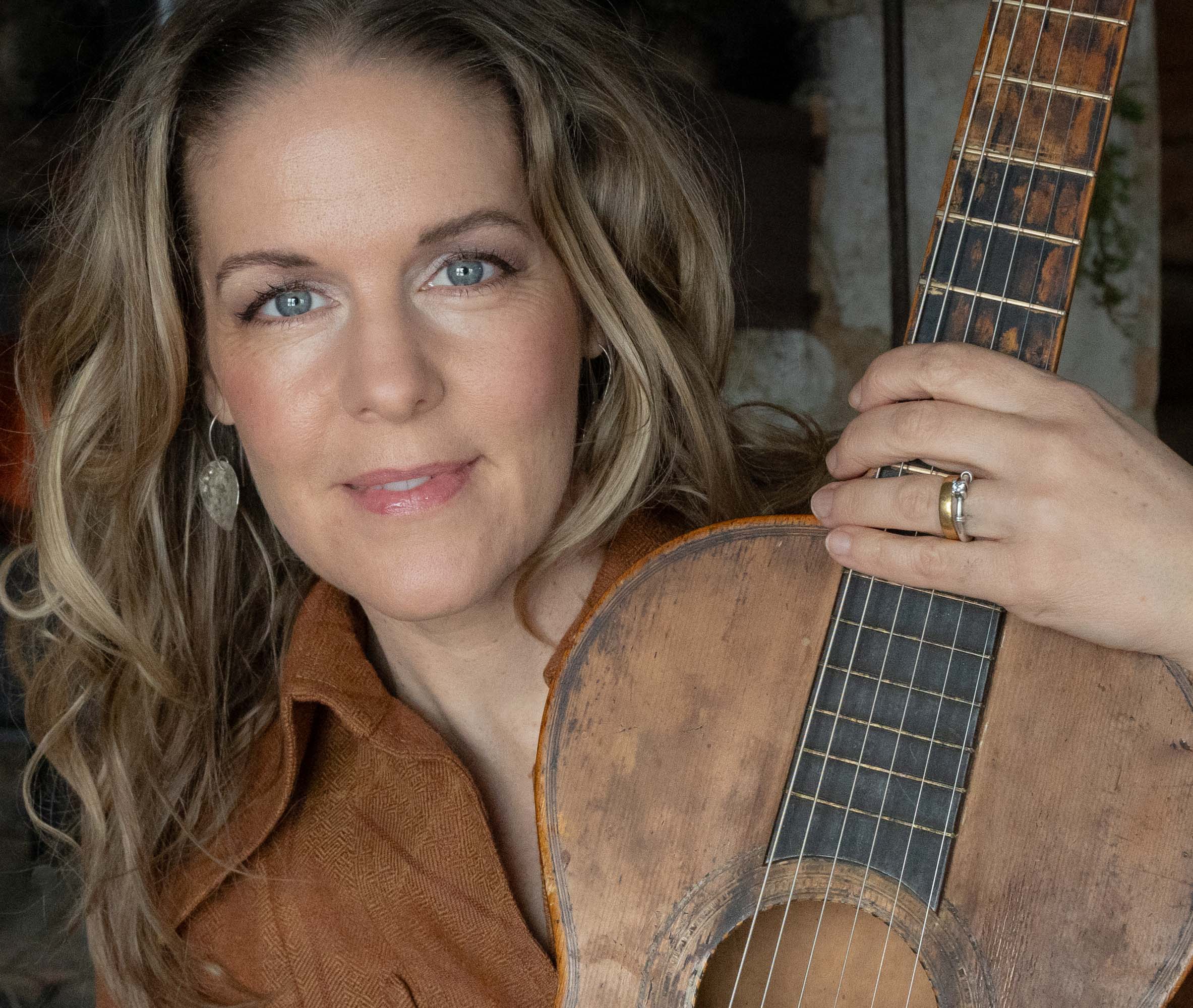 Sofia Karlsson håller i en akustisk gitarr.